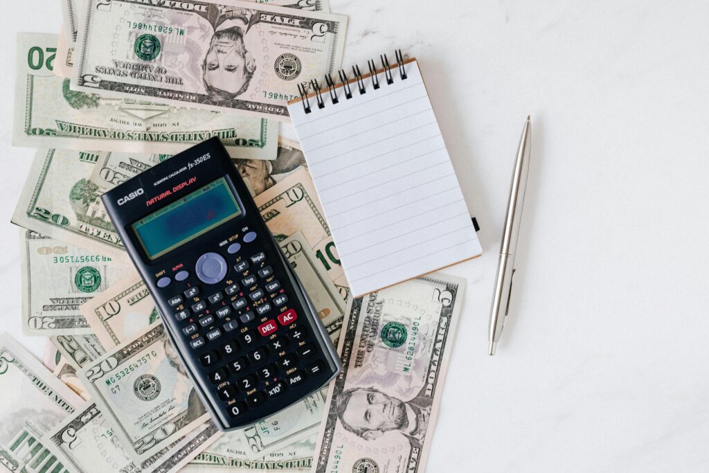 pexels-photo-4386373-4386373 Flat lay of US dollar bills with calculator and notebook for budgeting.