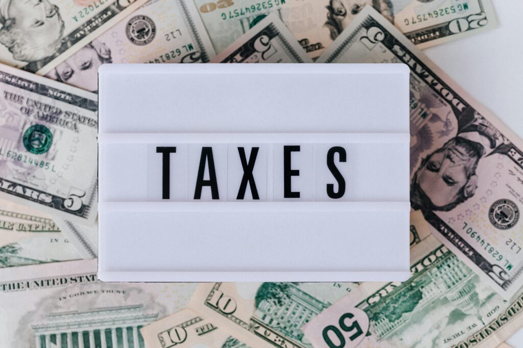 pexels-photo-4386372-4386372 Top view of white vintage light box with TAXES inscription placed on stack of USA dollar bills on white surface