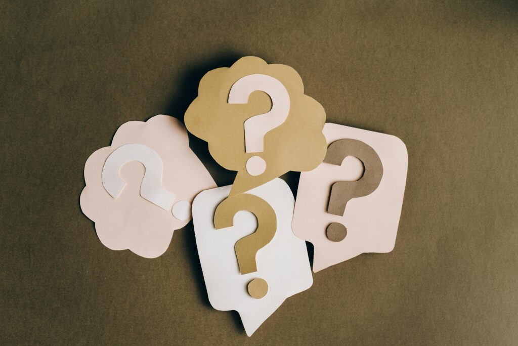 pexels-photo-5428836-5428836 Four paper cutouts of question marks in beige and white on a brown surface, symbolizing inquiry and curiosity.